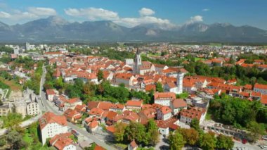 Slovenya 'nın arka planında dağ sırasına sahip Kranj kasabasının hava manzarası. Kranj, Slovenya 'nın üçüncü büyük kentidir. Drone yörünge atışı. Güneşli bir günde Kranj şehir manzarası.