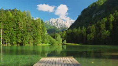 Slovenya 'nın Jezersko kentindeki Kamnik-Savinja Alpleri' ndeki Plansarsko Jezero Gölü 'nde güneşli bir yaz gününde dağ gölü iskelesi. Huzurlu dağ gölü olan Alp manzarasının güzelliği