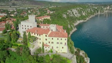 İtalya, Trieste körfezinin üzerindeki yüksek uçurumdaki eski Duino Kalesi. Tarihi Duino Şatosu, Avrupa ile İtalya 'nın Adriyatik kıyılarının havadan görünüşü. İnsansız hava aracı yörüngesi görüntüleri
