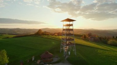 Polonya 'nın küçük Voyvoda bölgesinde yaz aylarında gün batımında bir gözlem kulesinin güzel hava manzarası. Kırsal alanda çarpıcı bir gün batımı. Tahta gözetleme kulesi.