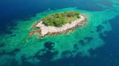 Hırvatistan 'ın Rab Adası' ndaki Gonar plajı yakınlarında kristal berrak deniz suyuna sahip küçük ıssız bir adanın hava manzarası. Hırvatistan 'ın Dalmaçya bölgesindeki Rab Adası' nın çarpıcı güzelliğini yansıtıyor.