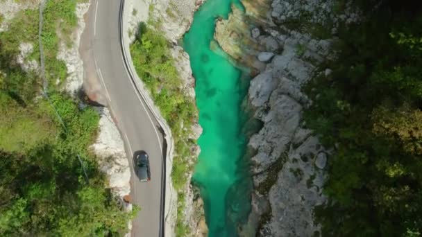 スロベニアのコカ川渓谷の狭い山道 スロベニアのソコ川のエメラルドウォーターで深い峡谷を運転する車の空中トップダウン追跡ショット — ストック動画