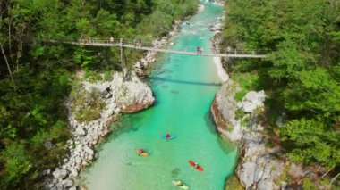 Slovenya 'nın Soca Nehri' nin zümrüt suları üzerinde bir asma köprü, hava manzarası. Soca Nehri kanyonu Slovenya 'da kano gezisi için tercih edilen bir yerdir. Slovenya 'daki Soca nehrinde kayakçılar
