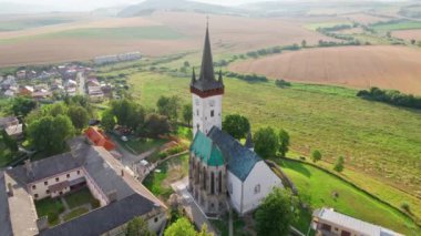 Slovakya 'nın Spissky Stvrtok kasabasındaki eski kilise. Yazın, tarihi bir kilise ve Slovakya 'da küçük bir köyle geleneksel kırsal manzaranın güzel hava manzarası. Drone yörünge atışı