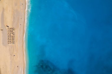 Beautiful Myrtos beach on a sunny summer day on Kefalonia island, Ionian sea, Greece. Idyllic white sandy beach on the shores of a beautiful turquoise sea. Empty beach with sunbed umbrellas clipart