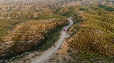 İspanya, Endülüs 'teki Gorafe Çölü' nün dağlık çöl manzarasından geçen kırmızı karavan. İspanya 'daki engebeli, kayalık Gorafe çölünün hava manzarası.. 