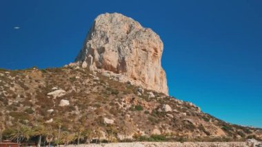 Calpe, İspanya - 10 Nisan 2024: Calp kasabasındaki güzel Cala el Raco plajı, İspanya. Costa Blanca Akdeniz kıyısı. Calpe şehri ve Penon de Ifac doğal parkı ikonik bir kayayla
