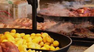 Polonya 'nın Krakow kentindeki bir Noel pazarında geleneksel Polonya sokak yemekleri. Bir şef rustik patates ve geleneksel ızgara ve pişirilmiş et hazırlar. Aralık 'ta Yıllık Noel Fuarı