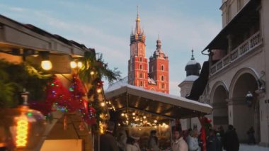 Krakow, Polonya - 5 Aralık 2024: Polonya 'nın Krakow kentindeki Ana Pazar Meydanı' nda geleneksel Noel fuarları. Güzel bir Noel tezgahı ve tatil aydınlatması. Krakow 'daki Mariacki Kilisesi ve Kumaş Salonu