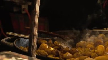 Bir şef Avrupa 'da geleneksel bir Noel pazarında kırsal patatesler hazırlar. Aralık ayındaki yıllık Noel festivalinde taze ve lezzetli sokak yemekleri. Döndürme çekimi