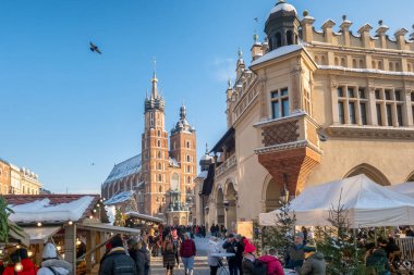 Krakow, Polonya - 5 Aralık 2024: Polonya 'nın Krakow kentindeki Ana Pazar Meydanı' nda geleneksel Noel fuarları. Güzel bir Noel tezgahı ve tatil aydınlatması. Krakow 'daki Mariacki Kilisesi ve Kumaş Salonu