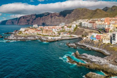 Günbatımında Tenerife adasındaki Los Gigantes manzarası, İspanya. Lüks oteller, kıyı kenti mimarisi ve arka planda görkemli yüksek uçurumlar, Tenerife, Kanarya adaları, İspanya