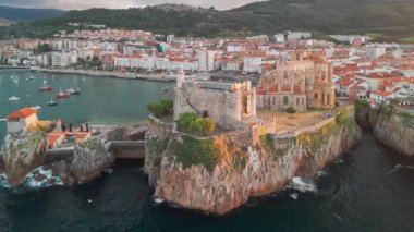 İspanya 'nın kuzeyinde Cantabria' da gün batımında Biscay Körfezi 'nde bulunan pitoresk bir liman şehri olan Castro Urdiales' in hava manzarası. Santa Maria de la Asuncion Kilisesi ve Santa Ana Şatosu Deniz feneri.