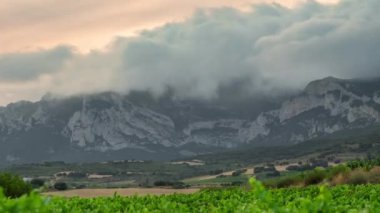 İspanya 'nın Rioja bölgesindeki üzüm bağlarının günbatımı zamanı. Bulutlar dağ sırasına inerek Rioja şarabında kullanılan üzümleri yetiştirmek için gerekli eşsiz bir mikro iklim yaratır.. 