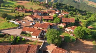 Kuzey İspanya, Cantabria 'daki Mogrovejo ortaçağ köyünün havadan görünüşü. Geleneksel evler, tarihi bir ortaçağ kulesi ve yazın Picos de Europa dağlarının görkemli zirveleri..