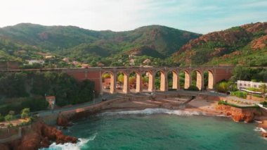 Antheor köyünün tarihi demiryolu köprüsü ve gün batımında Fransa Riviera, Provence-Alpes-Cote dAzur 'da Esterel Massif' in ikonik kırmızı kayaları ile hava manzarası.