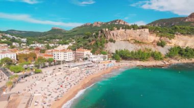 Fransa 'nın güneyindeki Fransız Rivierası' nda Cassis 'in hava görüntüsü. Sahnede uçuruma konmuş bir ortaçağ kalesi, kumlu bir plaj, turkuaz deniz suları ve kasabanın tarihi binaları yer alıyor.