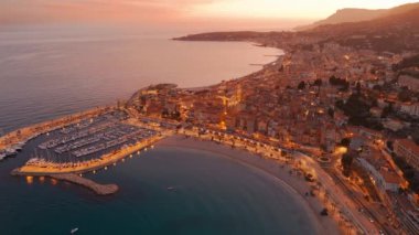 Fransız Rivierası, Fransa 'da Menton' un hava görüntüsü. Muhteşem bir günbatımı, renkli eski kasabanın üzerine sıcak bir ışık saçıyor. Alacakaranlıkta tarihi binalar, plaj ve şehir ışıkları. Fransız Cote dAzur