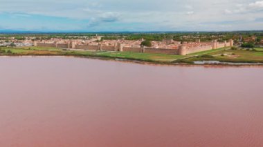 Güneşli bir günde, Fransa 'nın güneyindeki Camargue bölgesinde, pembe tuz gölü yakınlarındaki ortaçağ duvarlı Aigues-Mortes kasabasının havadan görünüşü. 