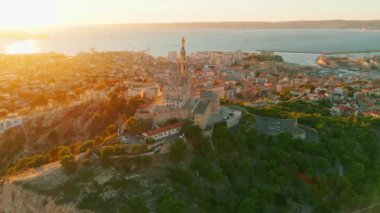 Notre Dame de la Garde 'ın ya da güney Fransa' da günbatımında Muhafız Kilisesi 'nin hava manzarası. Sıcak yaz akşamı ışığı Marsilya şehir manzarasını aydınlatıyor.. 