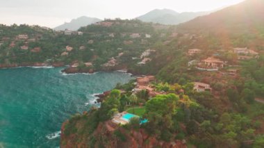 Günbatımında Fransız Riviera 'sı Provence-Alpes-Cote dAzur, Fransa' da Esterel Massif 'in ikonik kırmızı kayaları ile Antheor köyünün hava manzarası. Cote dAzur 'daki lüks villalar..