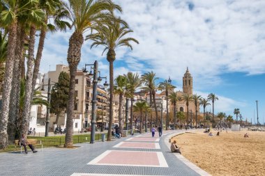 Sitges, İspanya - 3 Nisan 2024: Sitges tatil beldesi ve Iglesia de San Bartolome y Santa Tecla Kilisesi güneşli bir günde Katalonya, İspanya