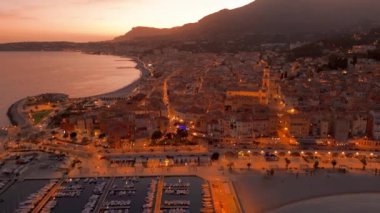 Fransız Rivierası, Fransa 'da Menton' un hava görüntüsü. Muhteşem bir günbatımı, renkli eski kasabanın üzerine sıcak bir ışık saçıyor. Alacakaranlıkta tarihi binalar, plaj ve şehir ışıkları. Fransız Cote dAzur