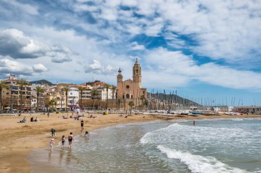 Sitges, İspanya - 3 Nisan 2024: Sitges tatil beldesi ve Iglesia de San Bartolome y Santa Tecla Kilisesi güneşli bir günde Katalonya, İspanya