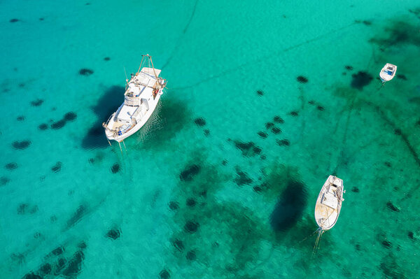 Small fishing boats anchoring in crystal clear sea water. Aerial view of a boat at anchor on turquoise water, Rab island, Croatia. Aerial view of the stunning Adriatic coast, Dalmatia region, Croatia