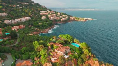 Günbatımında Fransız Riviera 'sı Provence-Alpes-Cote dAzur, Fransa' da Esterel Massif 'in ikonik kırmızı kayaları ile Antheor köyünün hava manzarası. Cote dAzur 'daki lüks villalar..