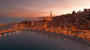 Fransız Rivierası, Fransa 'da Menton' un hava görüntüsü. Muhteşem bir günbatımı, renkli eski kasabanın üzerine sıcak bir ışık saçıyor. Alacakaranlıkta tarihi binalar, plaj ve şehir ışıkları. Fransız Cote dAzur