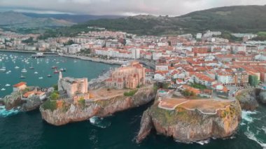 İspanya 'nın kuzeyinde Cantabria' da gün batımında Biscay Körfezi 'nde bulunan pitoresk bir liman şehri olan Castro Urdiales' in hava manzarası. Santa Maria de la Asuncion Kilisesi ve Santa Ana Şatosu Deniz feneri.