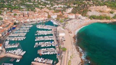 Fransa 'nın güneyindeki Fransız Rivierası' nda Cassis 'in hava görüntüsü. Sahnede uçuruma konmuş bir ortaçağ kalesi, kumlu bir plaj, turkuaz deniz suları ve kasabanın tarihi binaları yer alıyor.