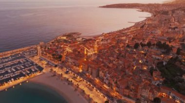 Fransız Rivierası, Fransa 'da Menton' un hava görüntüsü. Muhteşem bir günbatımı, renkli eski kasabanın üzerine sıcak bir ışık saçıyor. Alacakaranlıkta tarihi binalar, plaj ve şehir ışıkları. Fransız Cote dAzur