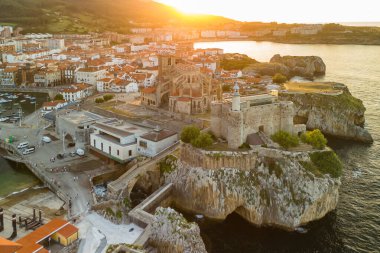 İspanya 'nın kuzeyinde Cantabria' da gün batımında Biscay Körfezi 'nde bulunan pitoresk bir liman şehri olan Castro Urdiales' in hava manzarası. Santa Maria de la Asuncion Kilisesi ve Santa Ana Şatosu Deniz feneri.