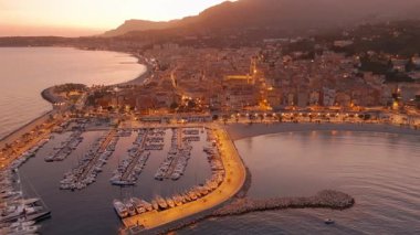 Fransız Rivierası, Fransa 'da Menton' un hava görüntüsü. Muhteşem bir günbatımı, renkli eski kasabanın üzerine sıcak bir ışık saçıyor. Alacakaranlıkta tarihi binalar, plaj ve şehir ışıkları. Fransız Cote dAzur