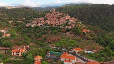 Gündoğumunda Fransa 'nın en güzel köylerinden biri olan ve popüler bir turizm beldesi olan Pirenes dağlarındaki ortaçağ tepe kasabası Eus' un hava manzarası.