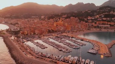 Fransız Rivierası, Fransa 'da Menton' un hava görüntüsü. Muhteşem bir günbatımı, renkli eski kasabanın üzerine sıcak bir ışık saçıyor. Alacakaranlıkta tarihi binalar, plaj ve şehir ışıkları. Fransız Cote dAzur