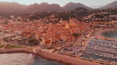 Fransız Rivierası, Fransa 'da Menton' un hava görüntüsü. Muhteşem bir günbatımı, renkli eski kasabanın üzerine sıcak bir ışık saçıyor. Alacakaranlıkta tarihi binalar, plaj ve şehir ışıkları. Fransız Cote dAzur