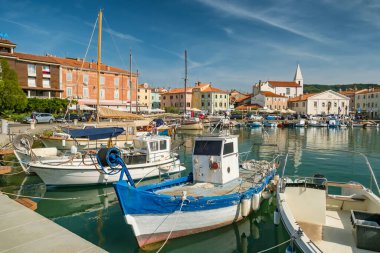 Slovenya 'nın Istria bölgesindeki Adriyatik kıyısındaki Picturesque Izola kasabası. Arka planda balıkçı tekneleri ve ortaçağ binaları olan büyüleyici bir liman.