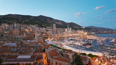 Geceleri Monako şehrinin gökdeleninin çarpıcı panoramik manzarası. Gökdelenler ve lüks yatlar, Herkül Limanı 'nı oluşturur. Fransız Rivierası 'nda Monte Carlo' nun tarihi mimarisi. Yavaş döndürme