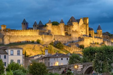 Ortaçağ şehri Carcassonne ve kalesi geceleri, güney Fransa 'da. İkonik ortaçağ kuleleriyle tarihi kale.