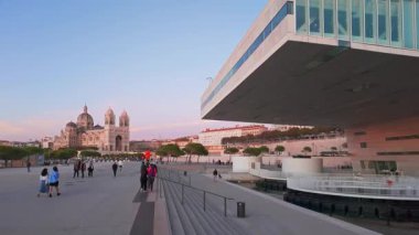 Marsilya, Fransa - 14 Eylül 2024: POV güney Fransa 'da Alacakaranlık' ta gezinti güvertesi Robert-Laffont 'unda yürürken vuruldu. Tarih Katedrali La Major ve modern müze binası.
