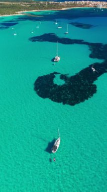 İspanya 'nın Balear Adaları, Mallorca' daki çarpıcı Akdeniz kıyılarının hava manzarası. Mallorca adasının turkuaz sularında huzur içinde demirlemiş yelkenliler..