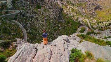 İspanya 'nın Balearic Adaları, Mallorca' daki ünlü Sa Calobra Yolu 'nun nefes kesici manzarasına hayran bir kadının uçurumun kenarında duruşu.. 