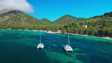 Playa de Formentor 'un Mallorca' daki Cala Pi de la Posada körfezindeki hava manzarası. Cap Formentor, Mayorka, Balearic Adaları, İspanya 'da turkuvaz sularında yüzen yelkenli tekneleriyle göz kamaştırıcı bir sahil..