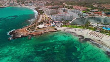 İspanya, Balearic Adaları, Mallorca 'daki Platja de sa Coma plajının havadan görüntüsü. Turkuaz suları olan büyüleyici beyaz kumsal yaz boyunca Mayorka adasında güzel bir tatil köyü ile çevrili..