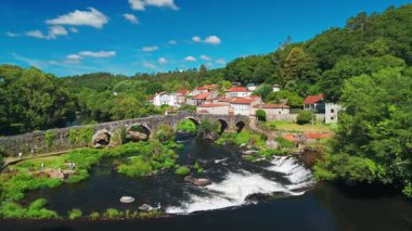 İspanya, Galiçya 'daki Camino de Santiago hac rotasındaki Ponte Maceira köyünün hava manzarası. Tarihi bir Roma köprüsü ve sakin bir kırsal alanda büyüleyici taş evler.
