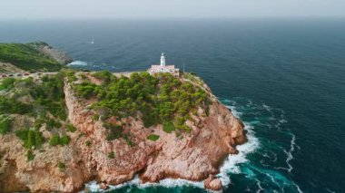 İspanya, Balearic Adaları, Mallorca 'daki Faro Capdepera deniz fenerinin hava manzarası. Manzaralı deniz feneri, Mayorka adasındaki Akdeniz manzaralı yüksek bir uçuruma tünemişti..