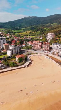 Güzel Bakio Hondartza plajı Bentalde, Bakio, Bask Ülkesi, İspanya. Bir grup sörfçü Kuzey İspanya 'daki çarpıcı kumsalda dalgaları yakalıyor.